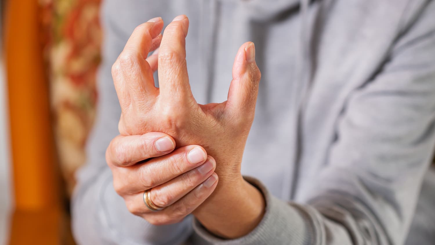 A woman with rheumatoid arthritis massages her swollen hand.