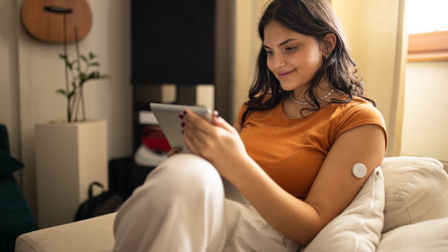 woman with continuous glucose monitor (CGM) on couch