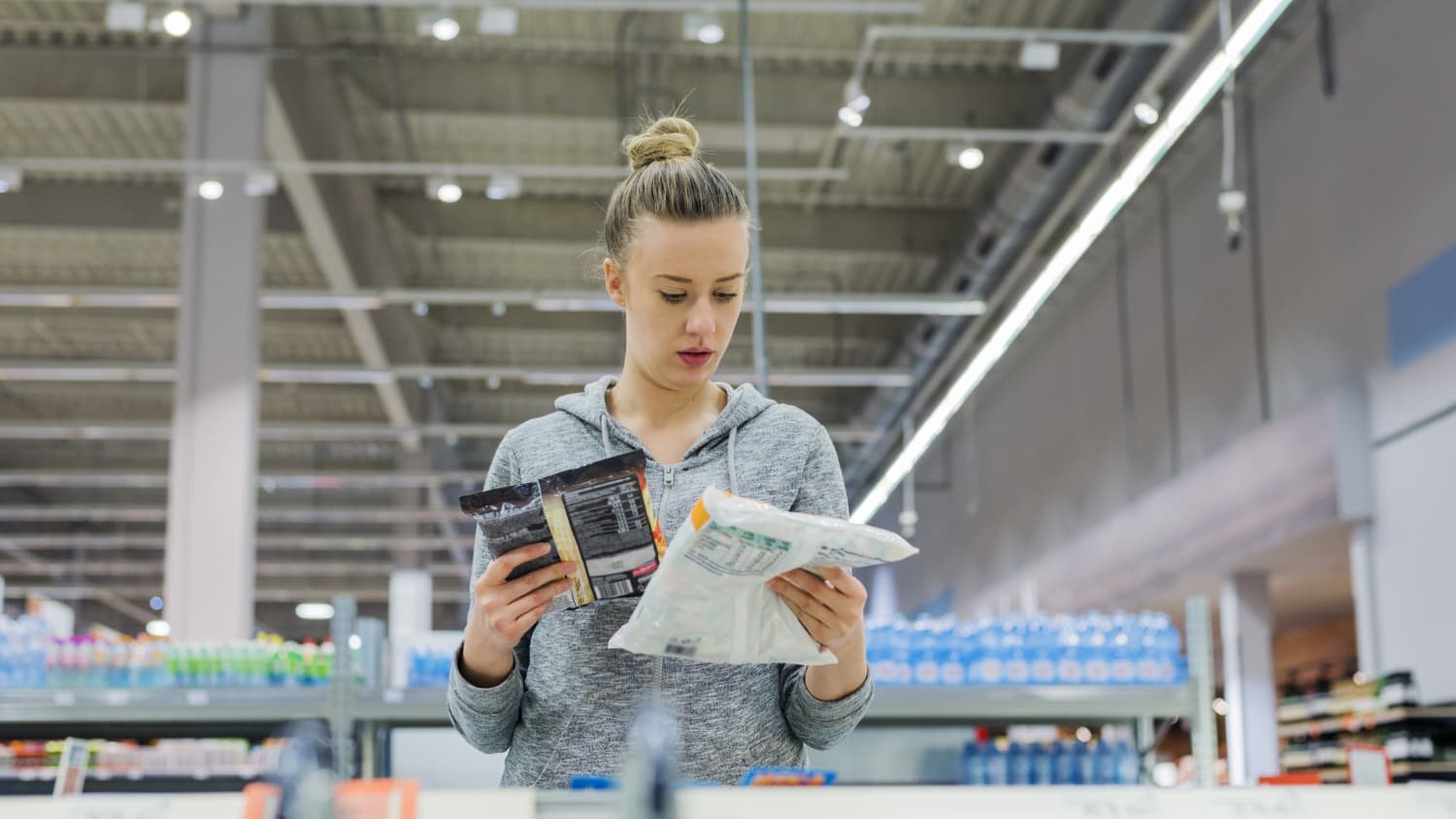 woman looking at food packages in grocery store to see if they're ultraprocessed