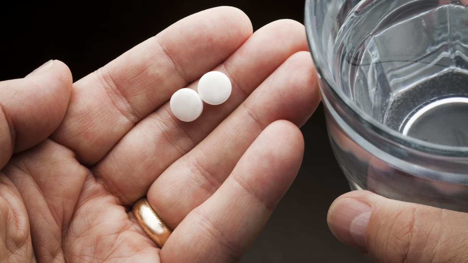 older person taking aspirin with water to prevent cardiovascular disease