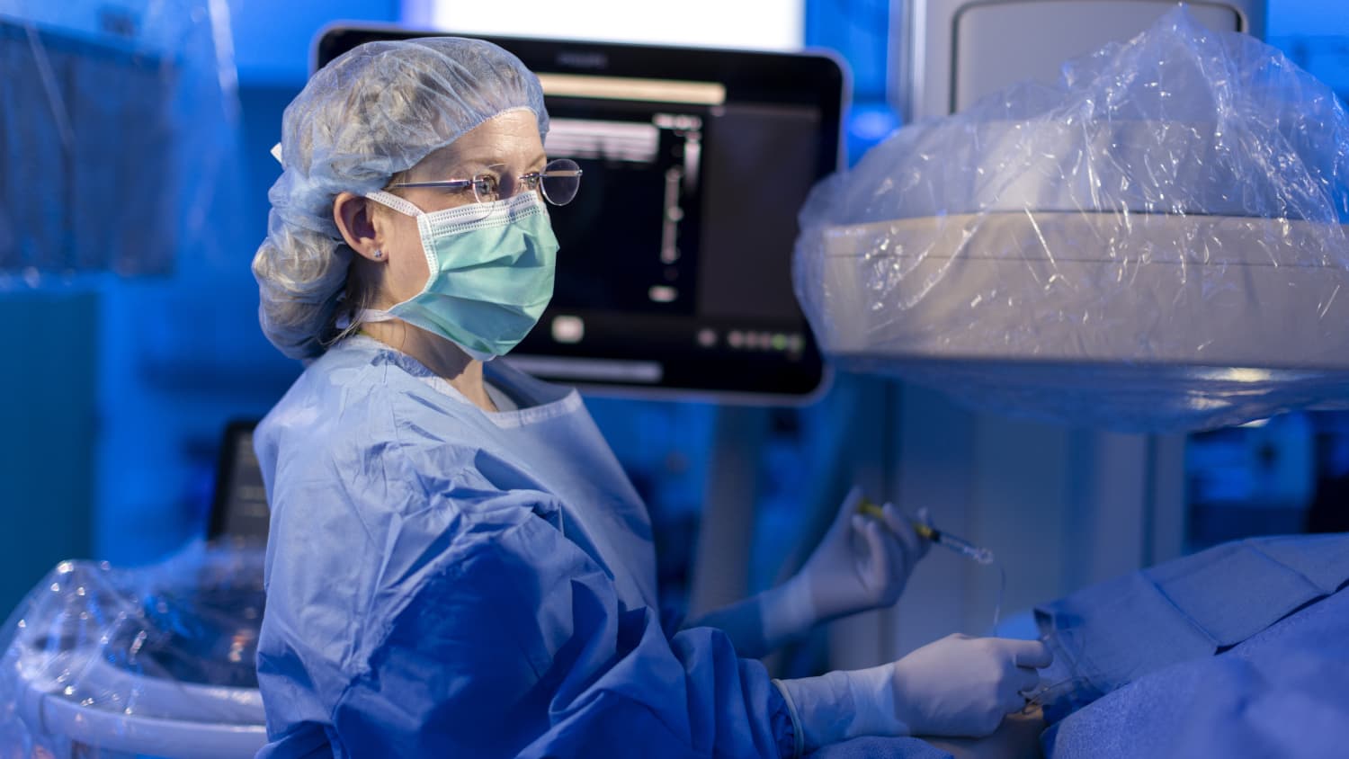 An interventional radiologist performs a procedure in an operating room.
