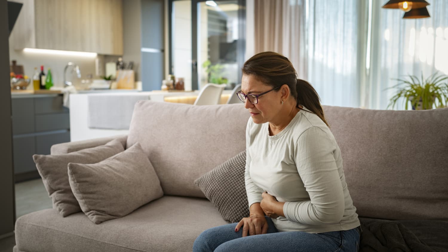 woman on couch in pain from a peptic ulcer