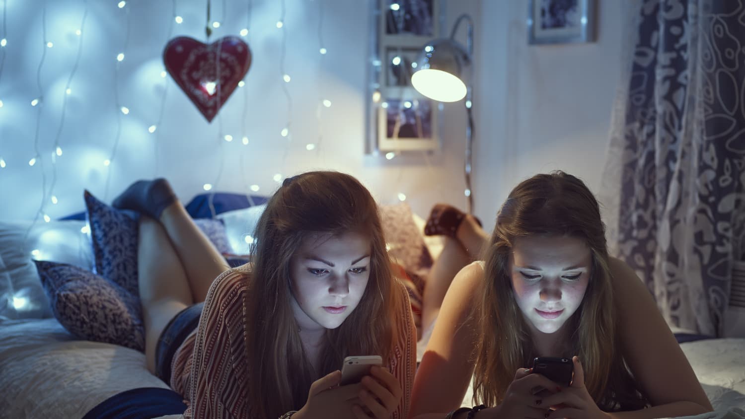 two teenage girls in their room on their phones, representing how social media can affect teens' mental health