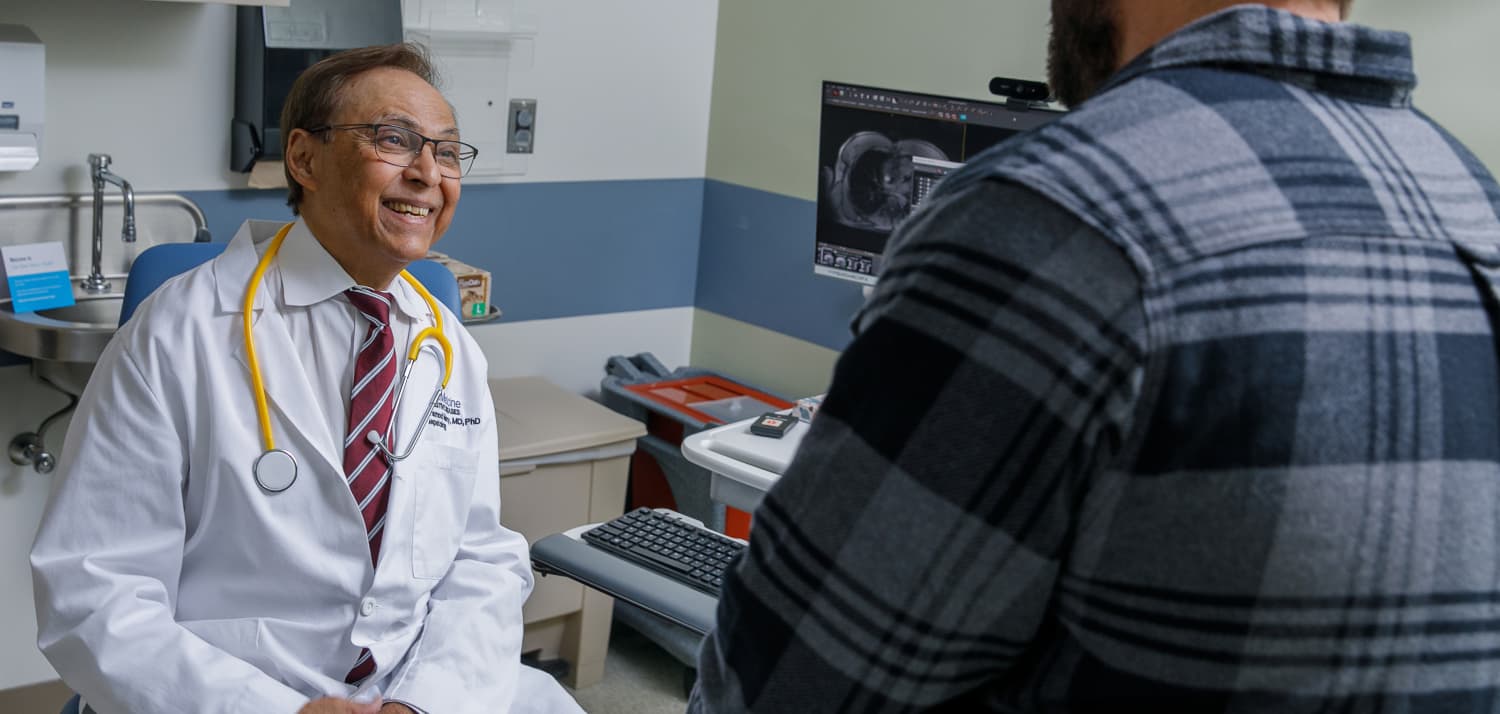 Pramod Mistry, MD, a Yale Medicine physician and Gaucher disease expert, talks to a patient in an exam room.