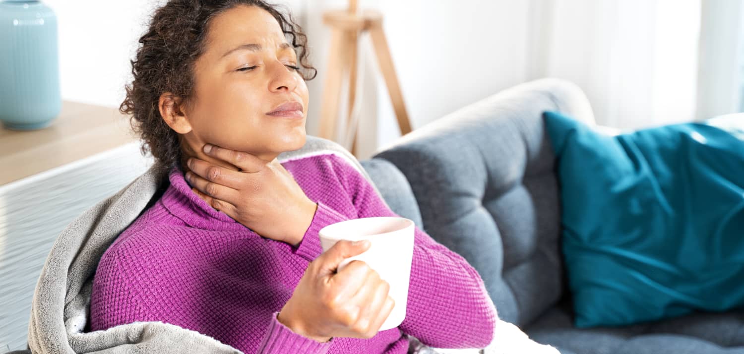 Woman with Sore Throat Sits on Sofa