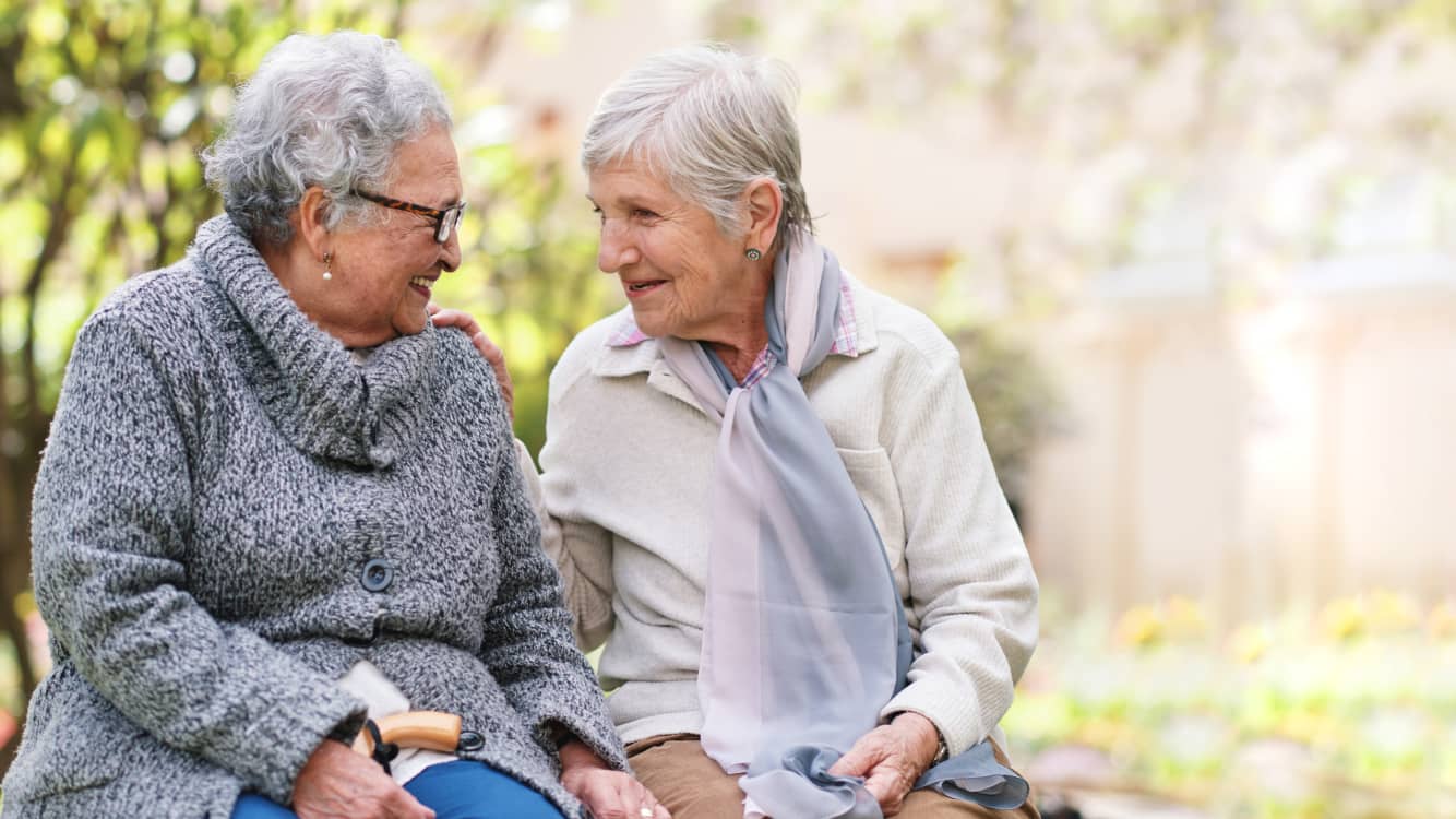 Two women sit together chatting. Socialization is one tool for preventing dementia.