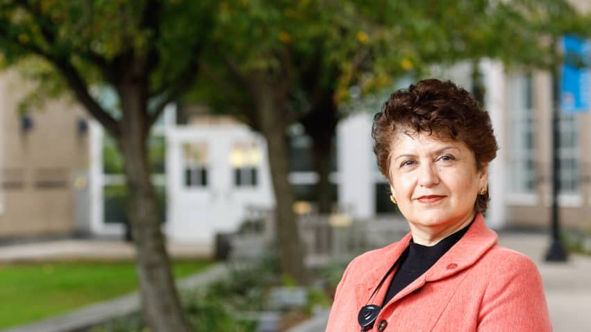 Dr. Lubna Pal portrait photo in outdoor courtyard with trees in the background.