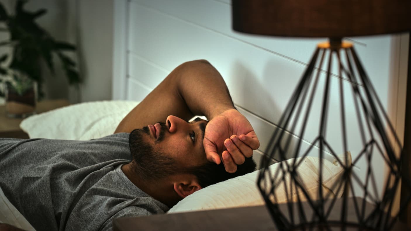 A man lying in bed struggling to sleep