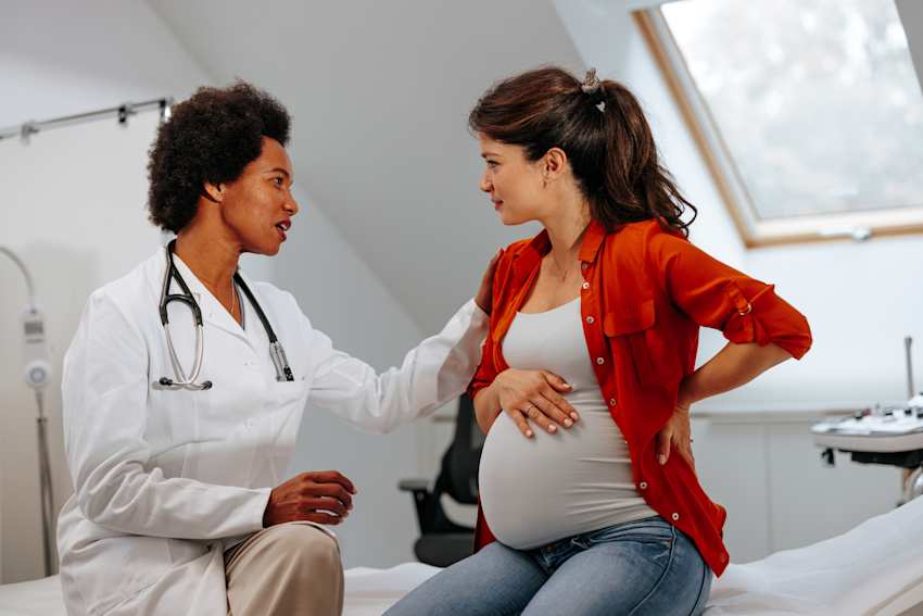 doctor advising a pregnant woman in a clinical examination room