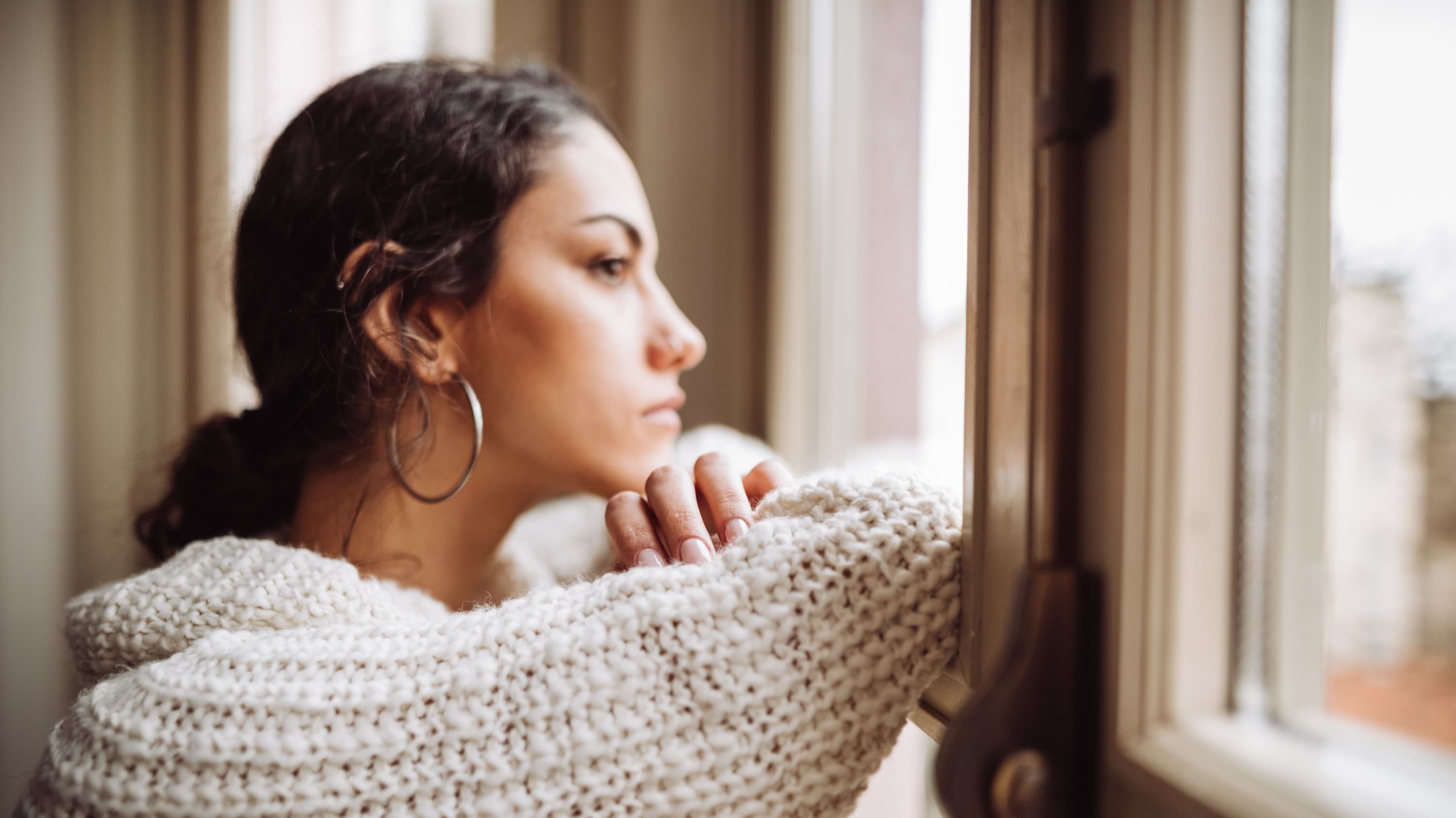 pensive woman in front of the window, thinking about advanced directives, especially amid COVID