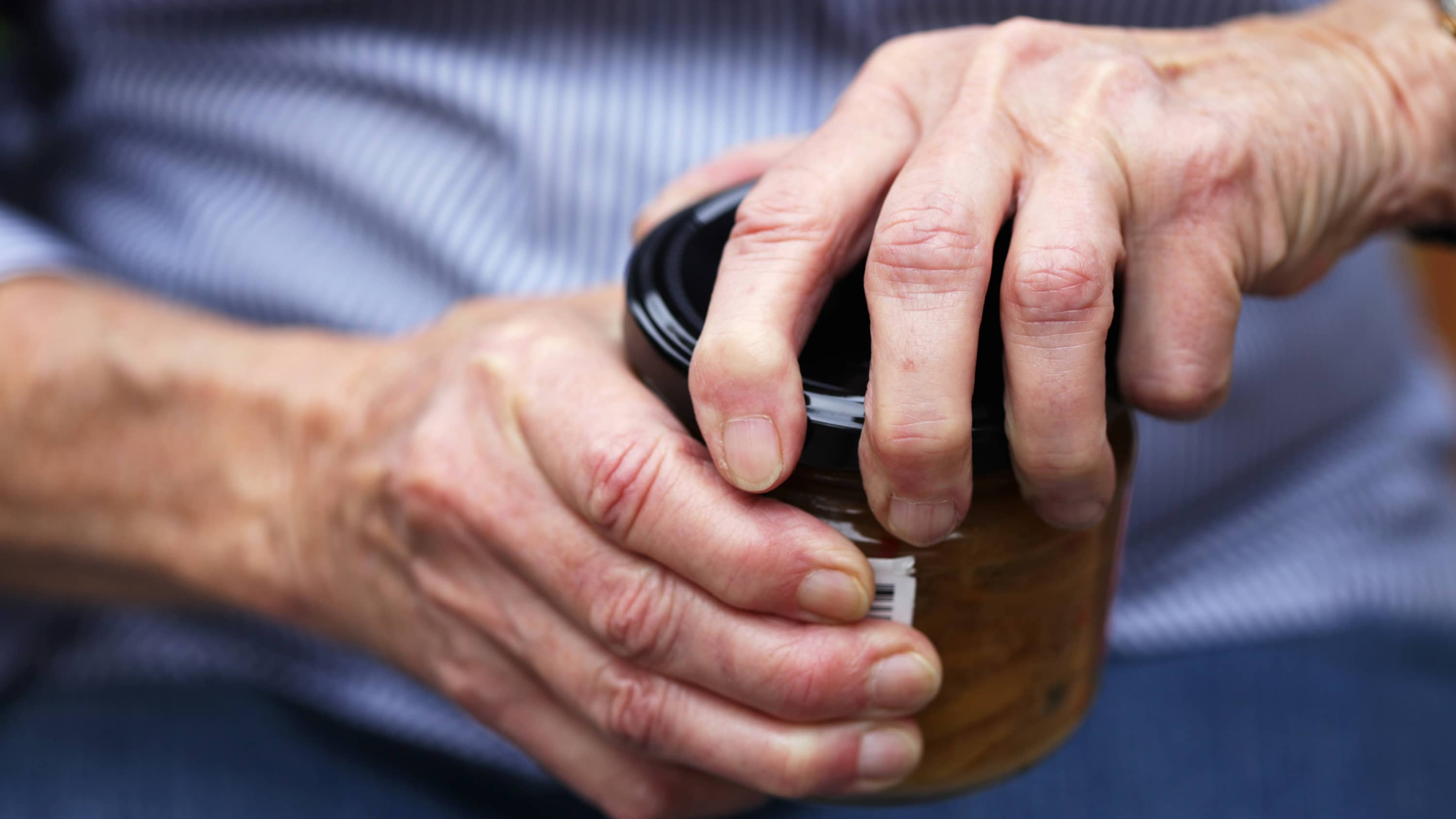 Older person with arthritis having difficulty opening a jar