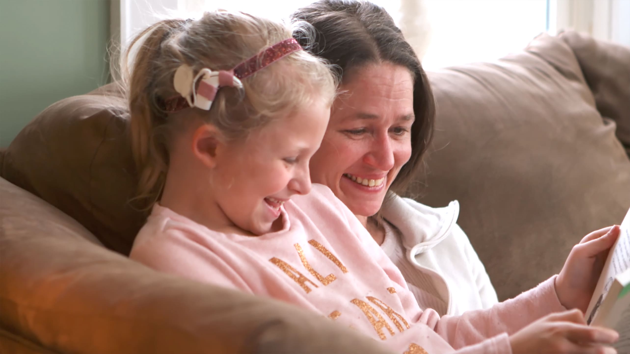 A little girl with a cochlear implant reads with her mother.